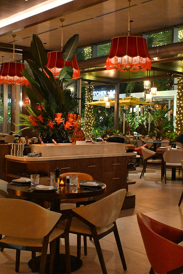 Red-fringed-lamps-hang-over-a-chic-restaurant-dining-room-filled-with-round-tables-and-lush-tropical-plants-interior-design