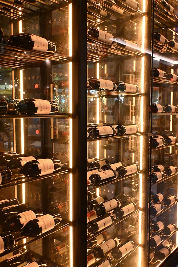 Rows-of-wine-bottles-are-stored-horizontally-within-sleek-glass-refrigerators-serafine-miami-interior-design-restaurant
