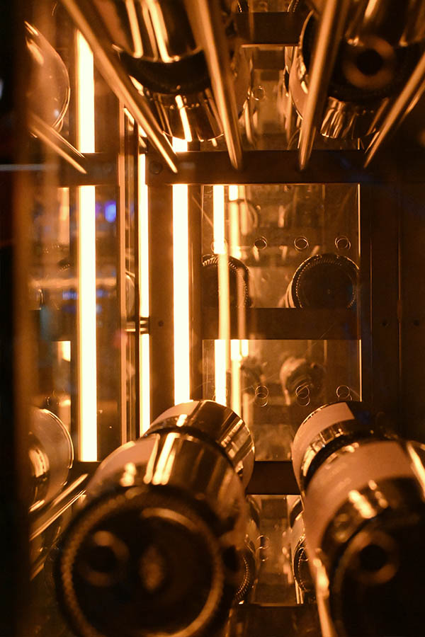 several-wine-bottles-resting-on-metal-racks-inside-a-glass-refrigerator-serafina-miami