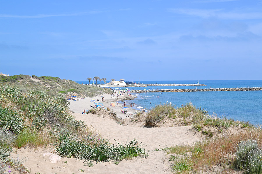 View-of-a-rocky-pier-and-distant-swimmers-Spain-beaches-Playa-Cabopino